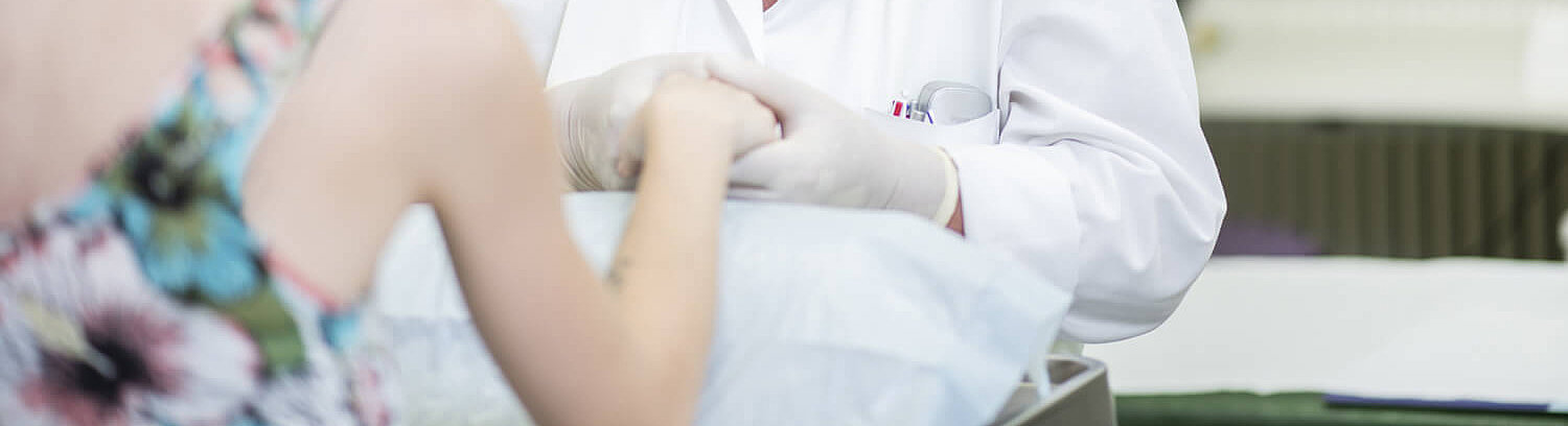 Ärztin unersucht Finger einer Rheumapatientin