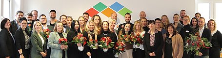  Eine große Gruppe stellt sich zum Gruppenbild auf. Zu sehen sind die Absolventen des Stationsleiterkurses, sie halten Blumen in den Händen, und deren Vorgesetzte.