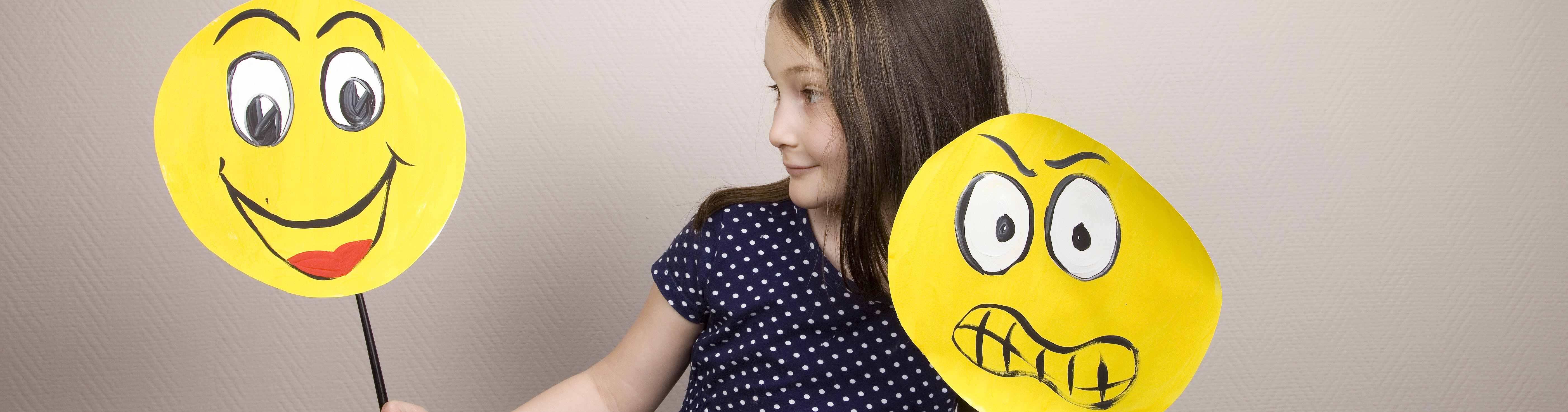 Mädchen hält Emojis mit lachendem und traurigem Gesicht hoch.